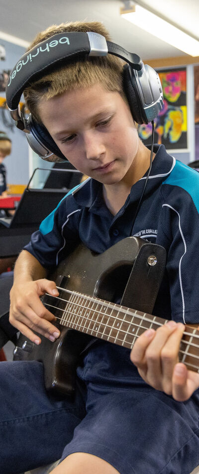 Attendance Student Playing the Bass Guitar in the Music Classroom