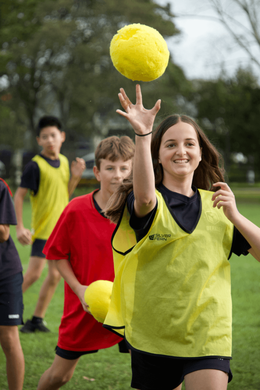 A Berkley student reaching for a ball during an outdoor dodgeball game