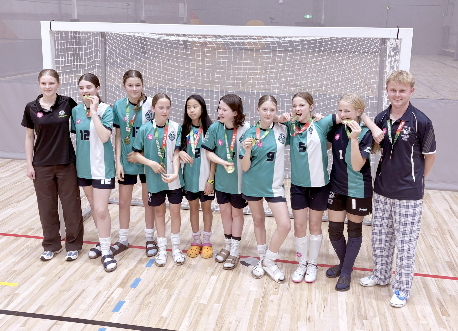 Berkley students and coaches celebrating together with their AIMS Games medals